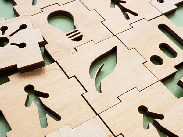 wooden interlocking puzzle pieces, one with leaf shape, one with person, one with lightbulb